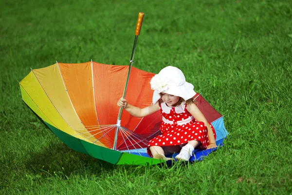 Liten flicka med en regnbåge paraply i park — Stockfoto