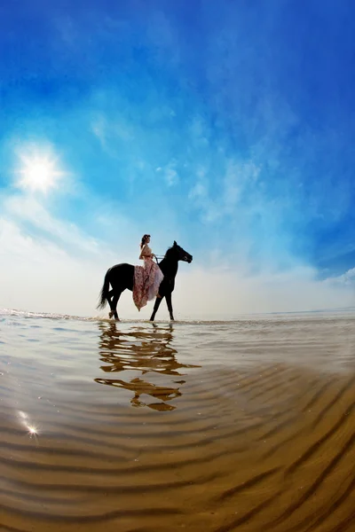 Vrouw op een paard door de zee — Stockfoto