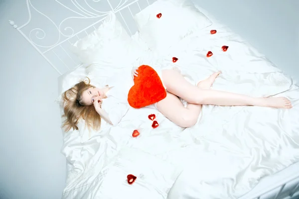 여자는 붉은 마음으로 침대에 누워 — 스톡 사진