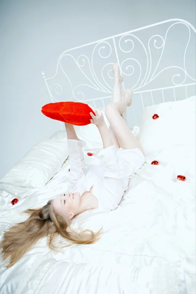 Menina deitada na cama com um coração vermelho — Fotografia de Stock