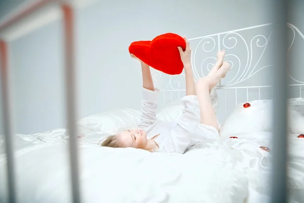 女孩躺在床上，一颗红色的心 — 图库照片