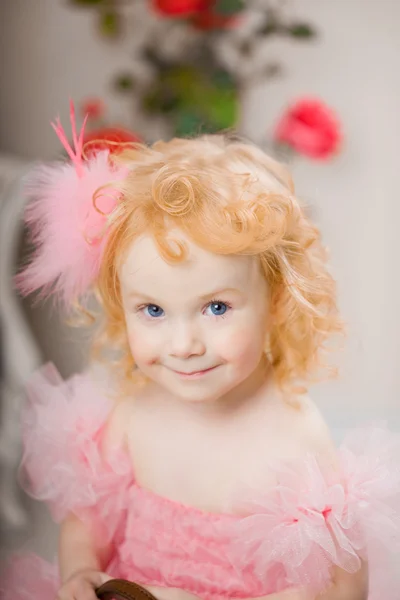 Criança em um vestido rosa em um cavalo de brinquedo — Fotografia de Stock