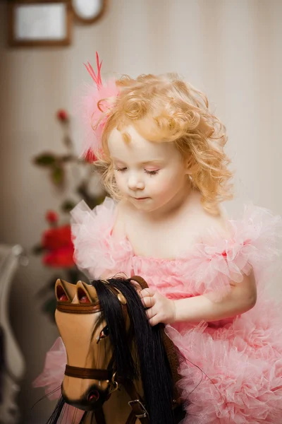子供におもちゃの馬にピンクのドレスで — ストック写真