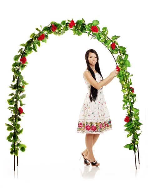 Ñute girl near the arch entwined by roses — Zdjęcie stockowe