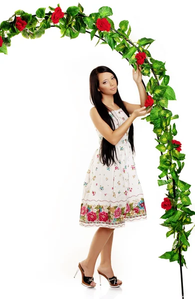 Девушка рядом с аркой, переплетенная розами — стоковое фото