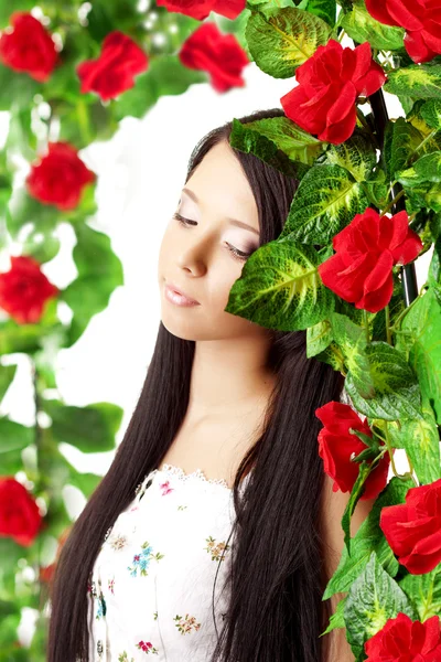 Красивая девушка с ярким макияжем среди роз — стоковое фото