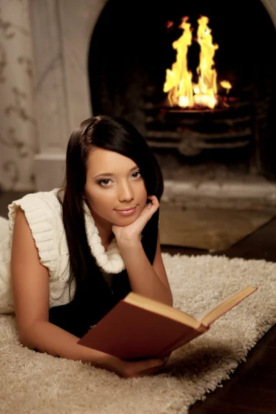 横たわった少女付近の暖炉と本を読む — ストック写真