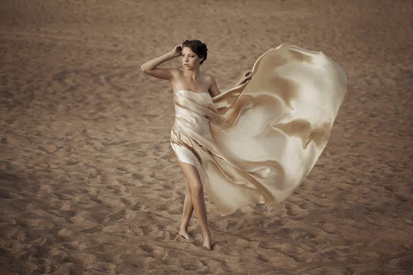 Kvinna i flygande guld tyg — Stockfoto