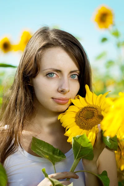 Vrouw met blauwe ogen met zonnebloemen — Stockfoto