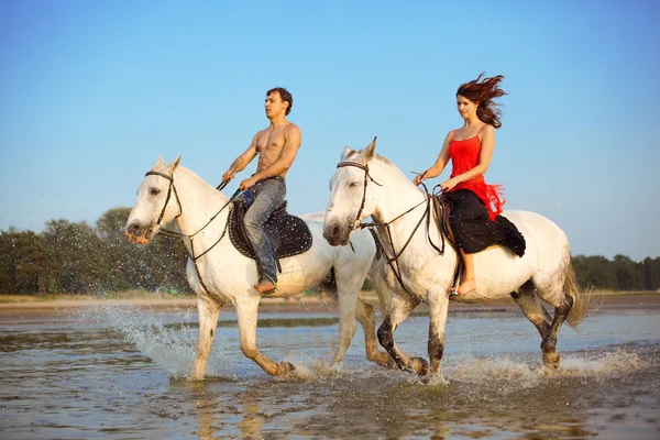 Young couple in the sea on horseback Stock Photo