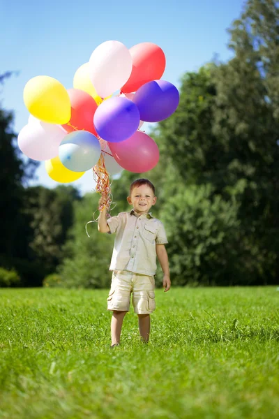 Enfant avec un tas de ballons dans les mains Images De Stock Libres De Droits