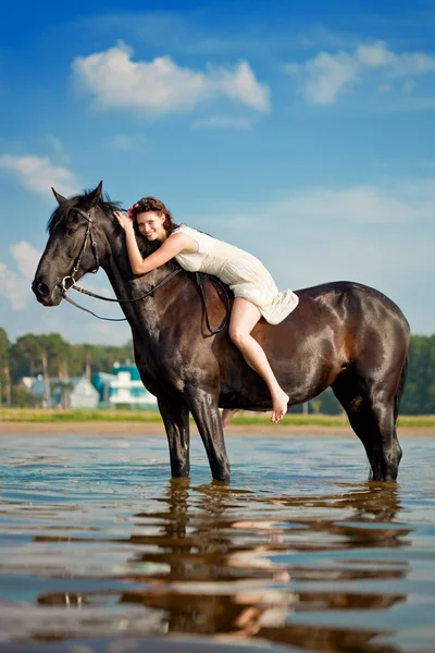 Vrouw op een paard door de zee Stockafbeelding