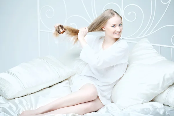 Flicka kamma hennes hår i sängen Stockfoto