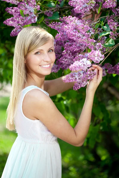 Lachende mooie vrouw met violette bloemen — Stockfoto