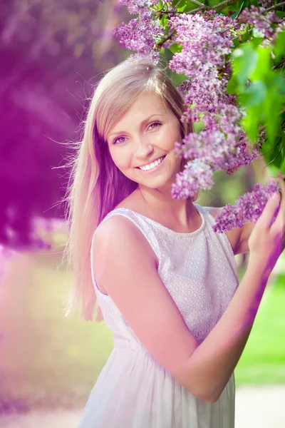 Χαμογελώντας όμορφη γυναίκα με ιώδη λουλούδια — Φωτογραφία Αρχείου