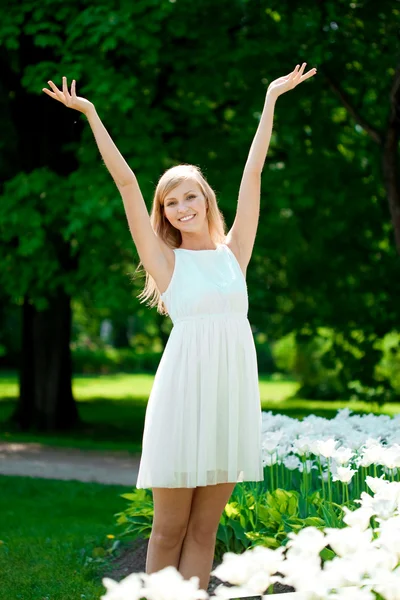 Unga leende kvinna med armar upp utomhus — Stockfoto
