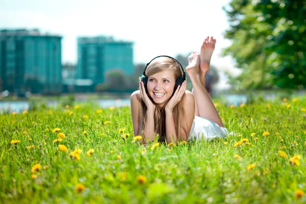 屋外のヘッドフォンで音楽を聴く女性女性の笑みを浮かべてください。 — ストック写真