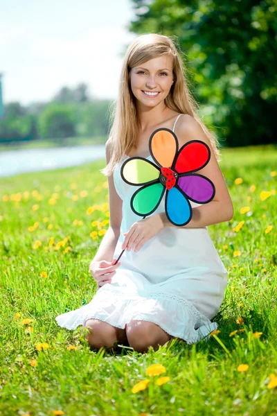 Усміхнена жінка з веселкою квітка на відкритому повітрі — стокове фото