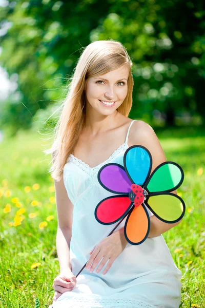 Mulher sorridente com uma flor de arco-íris ao ar livre — Fotografia de Stock
