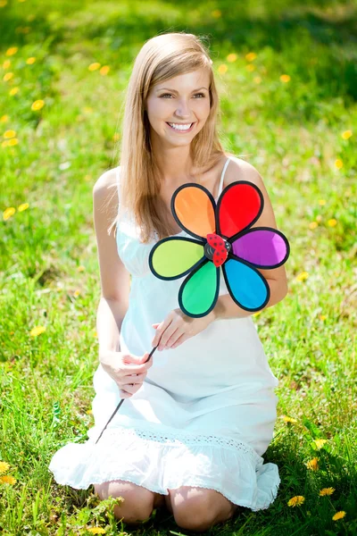 Lachende vrouw met een regenboog bloem buitenshuis — Stockfoto