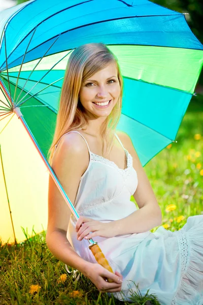 Mujer sonriente con un paraguas de arco iris al aire libre — Foto de Stock