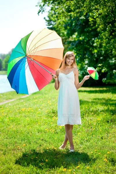Hermosa mujer sonriente con dos paraguas de arco iris, al aire libre —  Fotos de Stock