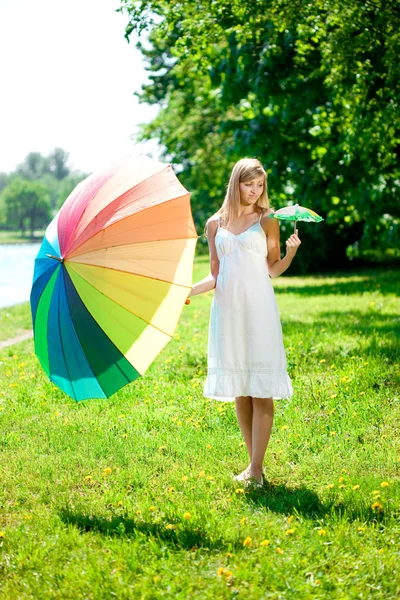 Vackra leende kvinna med två rainbow paraplyer, utomhus — Stockfoto