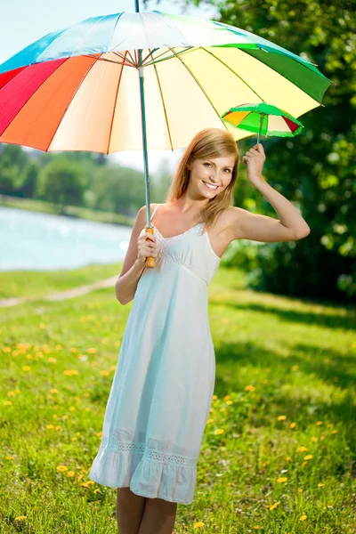 Улыбающаяся женщина с радужным зонтиком на улице — стоковое фото