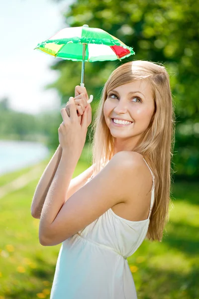 Donna sorridente con un ombrello arcobaleno all'aperto — Foto Stock