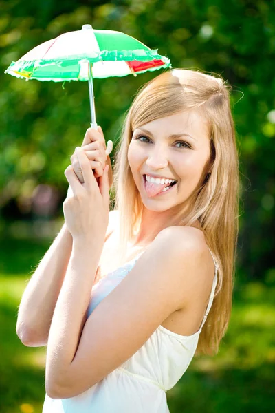 Lachende vrouw met een regenboog paraplu buitenshuis — Stockfoto