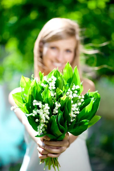 Молода жінка посміхається і дарує букет квітів — стокове фото