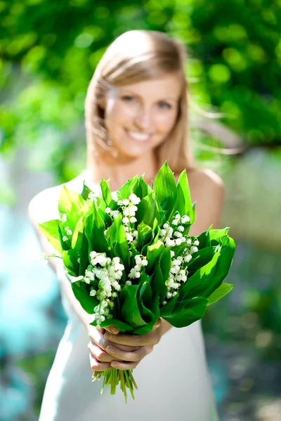 Νεαρή γυναίκα να χαμογελά και να δώσει μια ανθοδέσμη των λουλουδιών — Φωτογραφία Αρχείου