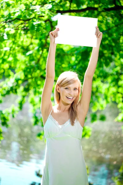 Szczęśliwy piękna kobieta uśmiechający się z pustym plakat na zewnątrz — Zdjęcie stockowe
