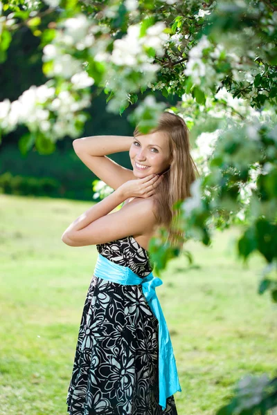 Lachende mooie vrouw met bloeiende boom — Stockfoto