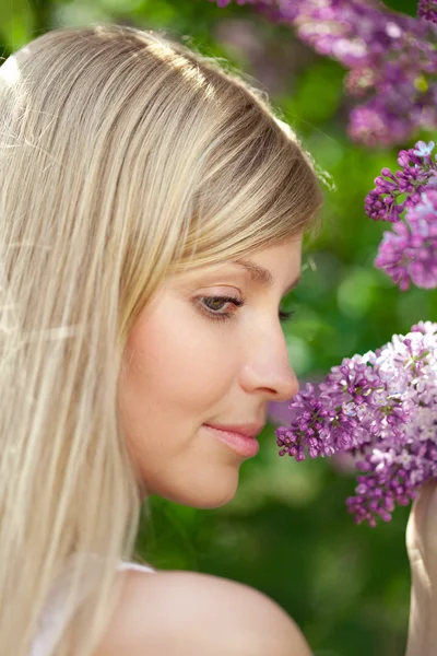 Lachende mooie vrouw met violette bloemen Stockfoto