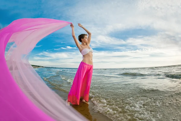 Mulher com um tecido nas mãos na praia — Fotografia de Stock
