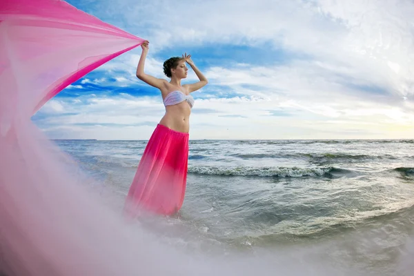 Mulher com um tecido nas mãos na praia — Fotografia de Stock