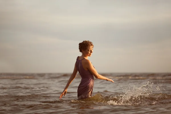 Kobieta na plaży o zachodzie słońca. — Zdjęcie stockowe