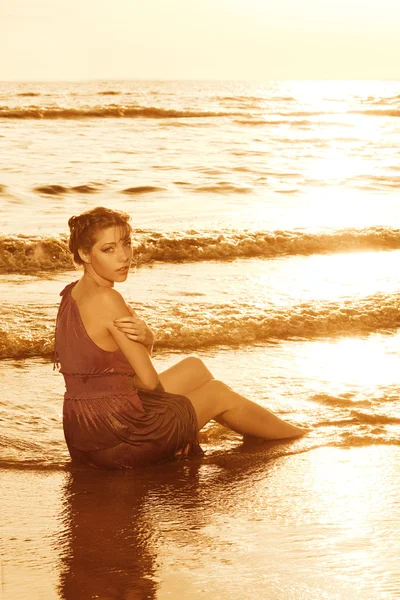 Vrouw op het strand bij zonsondergang. — Stockfoto