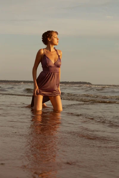 Kvinna på stranden vid solnedgången. — Stockfoto