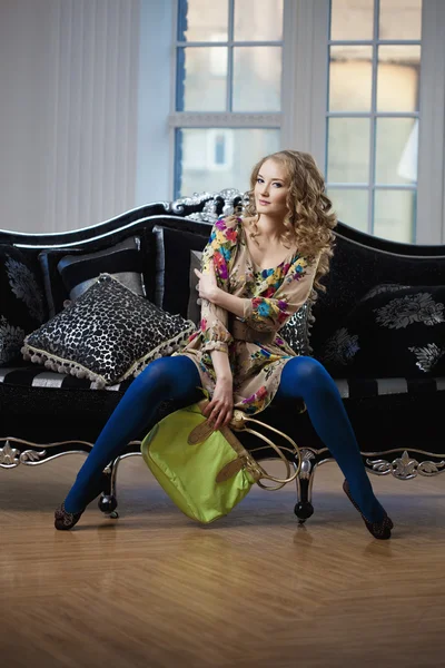Mujer de belleza en un lujoso sofá con bolso — Foto de Stock