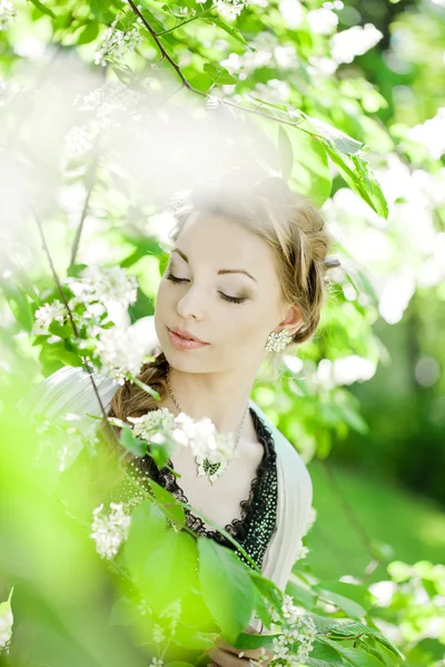 Mulher com uma trança de cabelo em um parque florescente . — Fotografia de Stock
