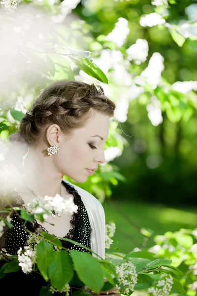Femme avec une tresse de cheveux dans un parc en fleurs . — Photo