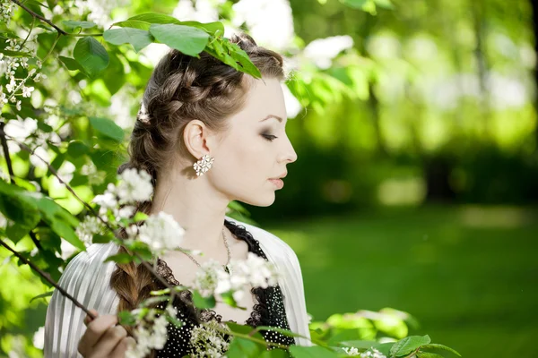 Frau mit Haarzopf in einem blühenden Park. — Stockfoto