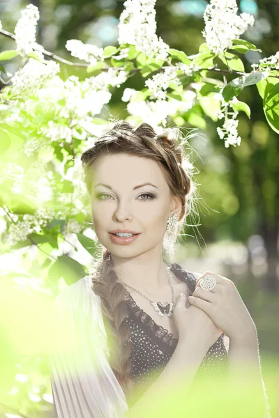 Kvinna med en hår fläta i en blomstrande park. — Stockfoto