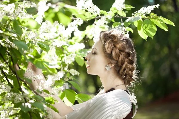 Mulher com uma trança de cabelo em um parque florescente . — Fotografia de Stock