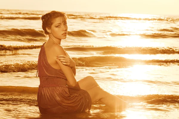 Femme sur la plage au coucher du soleil. Image En Vente