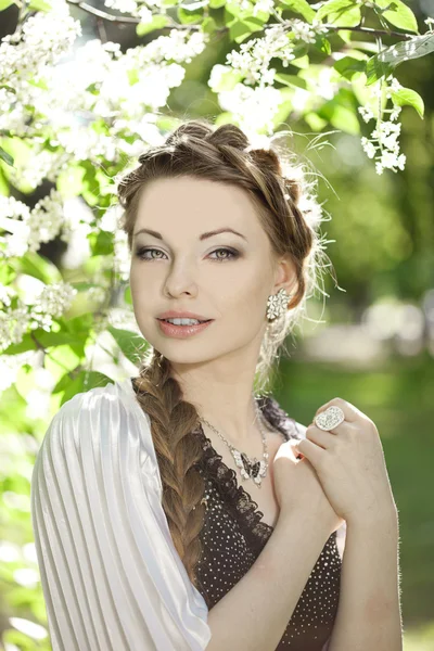 Woman with a hair braid in a blossoming park. Stock Image