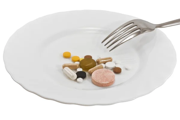 Pilules sur une assiette avec une fourchette — Photo
