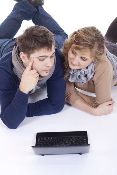 Unga par som ligger på golvet medan du använder en bärbar dator — Stockfoto